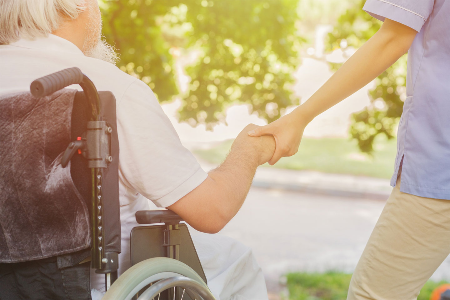車椅子の高齢者と介護スタッフが手を取り合う様子