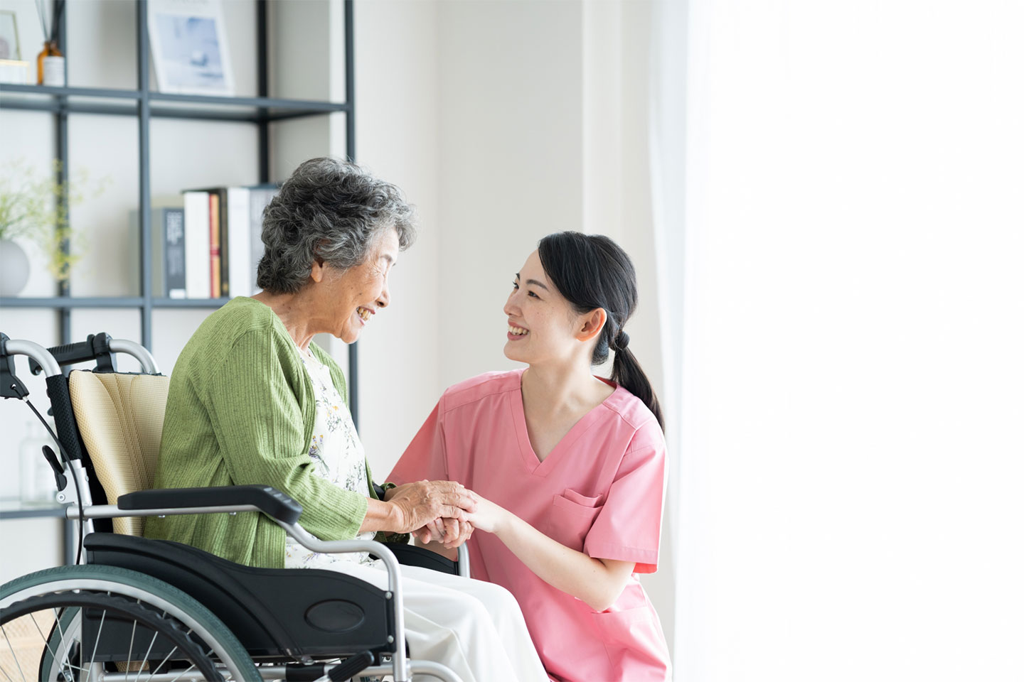 車椅子の女性と介護スタッフの笑顔のやり取り